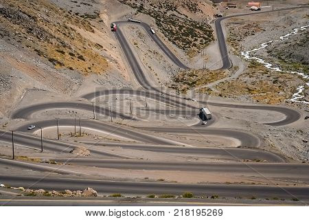 Cars trucks and lorries driving on the twisting and turning switchback road through high Andes in Chile, South America