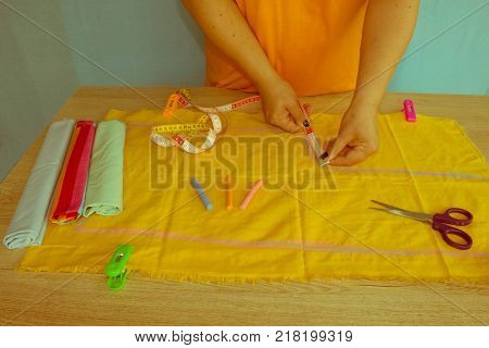 woman hands sewing yellow cloth outdoors. Tailor hands working with scissor and suit textile cloth