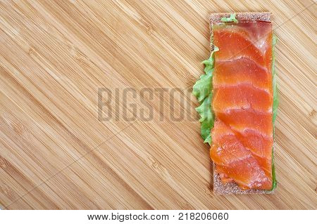 Low caloric open sandwich with red fish on wooden background.