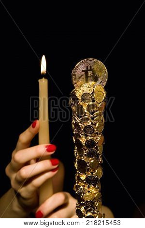 Female hands hold a candle in front of bitkoyn. Crypto currency.