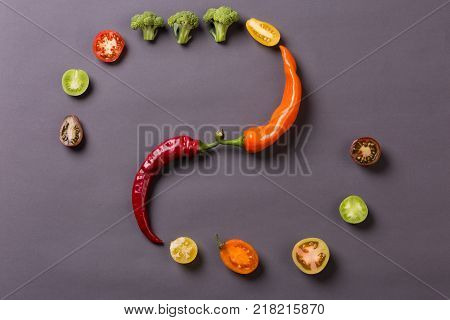 Chilli peppers with tomatoes and broccoli on grey background