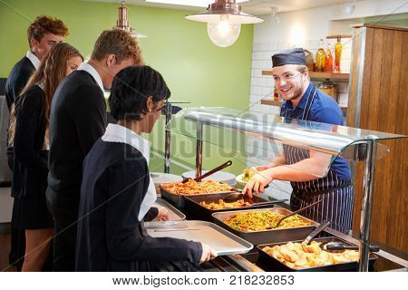 Teenage Students Being Served Meal In School Canteen