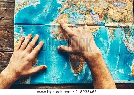 Mens Hands On A Paper Map Of The World Indicate The Final Destination Top View