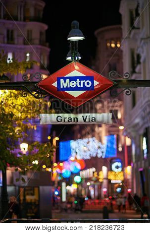 Madrid, Spain - December 12, 2017. Gran Via metro station signboard at night with Gran Via and Hortaleza streets illuminated by christmas lights, located in central Madrid. View from Montera street.