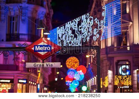 Madrid, Spain - December 12, 2017. Gran Via metro station signboard at night with Gran Via and Hortaleza streets illuminated by christmas lights, located in central Madrid. View from Montera street.