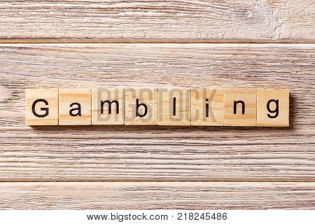 Gambling word written on wood block. Gambling text on table concept.