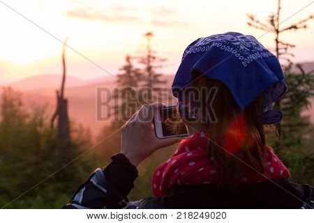 A young girl takes photos of nature on the phone