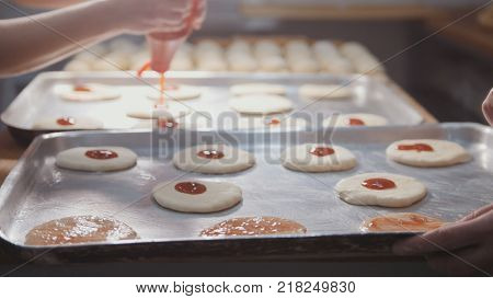 Cooks prepare a mini pizza, place the tomato paste close-up