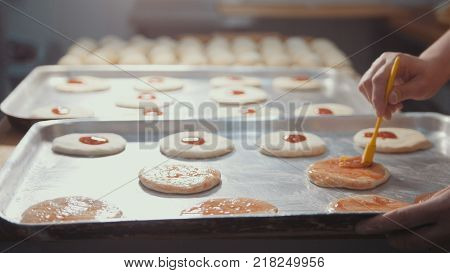 Cooks in the kitchen prepare a mini pizza, place the tomato paste, close-up