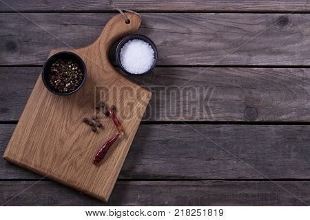 Mock up for restaraunt menu or recipe. Wooden cutting board with salt and pepper on the gray rustic background. Copy space.