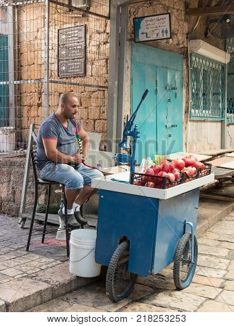 Acre Israel November 03 2017 : The seller of freshly squeezed juices sits and smokes nargila in anticipation of buyers on the market in the old city of Acre in Israel