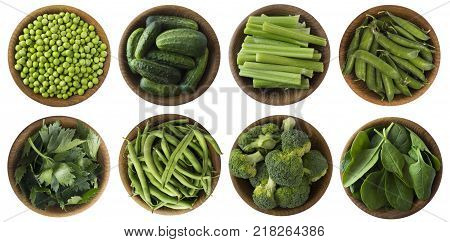 Green vegetables isolated on a white background. Brocoli green peas cucumbers and leaves parsley celery spinach in wooden bowl with copy space for text. Top view.