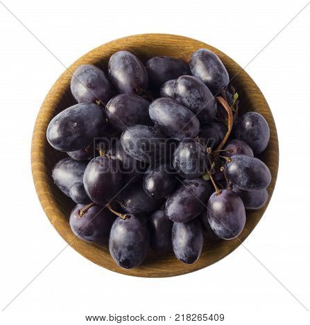 Grapes in a wooden bowl isolated on white background. Blue grapes with copy space for text. egetarian or healthy eating. Top view.