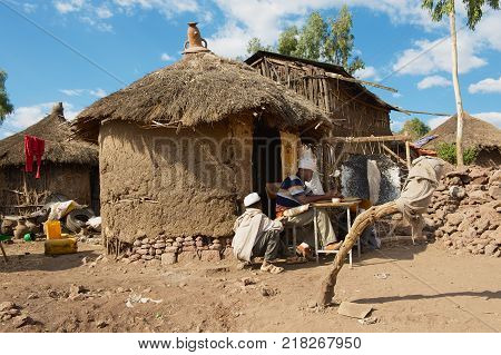 LALIBELA, ETHIOPIA - JANUARY 27, 2010: Unidentified people paint and read at the house entrance in Lalibela, Ethiopia. Ethiopia has one of the highest levels of illiteracy in the world.