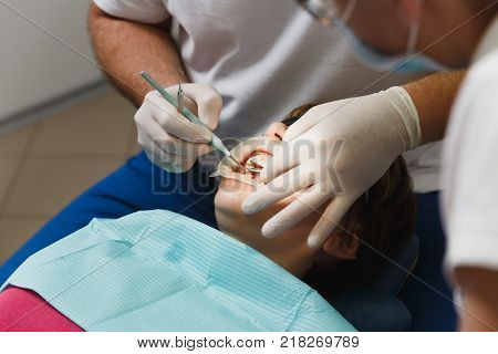 Process Of Preparing And Installing Dental Ceramic Crown. Male Professional Dentist And Female Assis