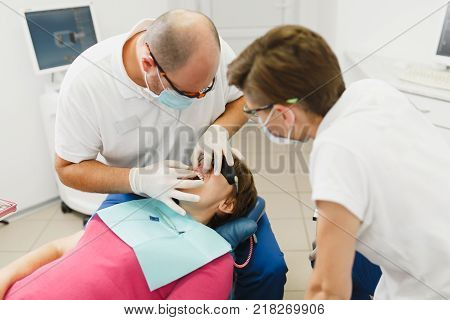 Process Of Preparing And Installing Dental Ceramic Crown. Male Professional Dentist And Female Assis