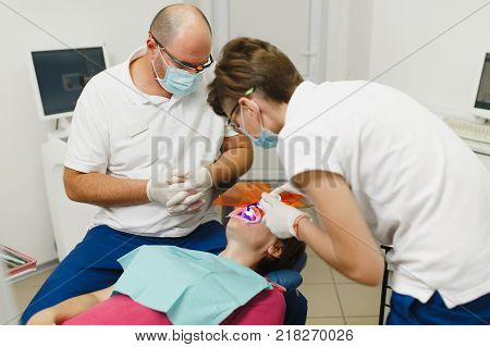 Process Of Preparing And Installing Dental Ceramic Crown. Male Professional Dentist And Female Assis