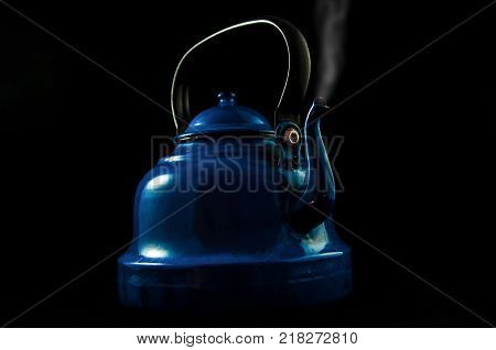 Blue teapot with steam isolated on black.