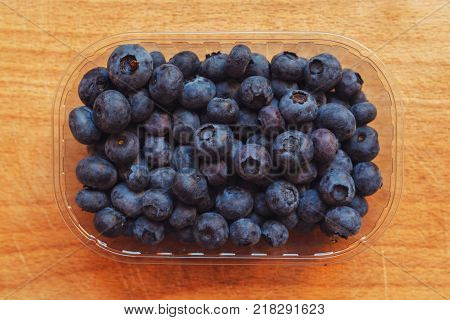 Blueberries myrtilles in plastic container box on wooden table