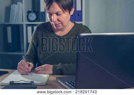 Female entrepreneur doing start up business paperwork in home office interior