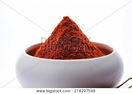Red Chilly Powder in a bowl with dried red chillies over colourful background or pile of red chilli powder over plain background
