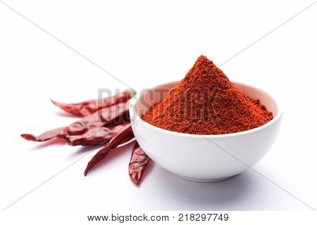 Red Chilly Powder in a bowl with dried red chillies over colourful background or pile of red chilli powder over plain background