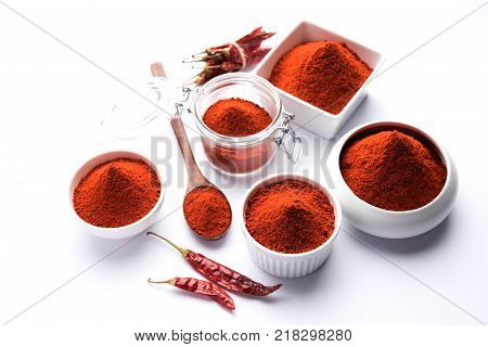 Red Chilly Powder in a bowl with dried red chillies over colourful background or pile of red chilli powder over plain background