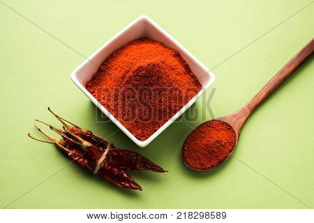 Red Chilly Powder in a bowl with dried red chillies over colourful background or pile of red chilli powder over plain background