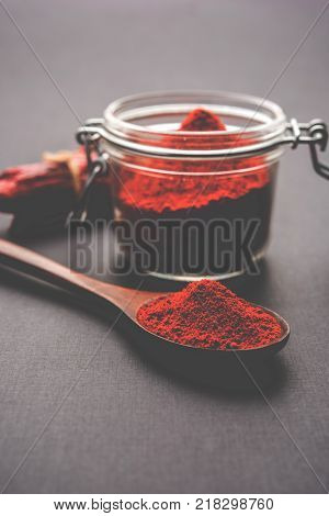 Red Chilly Powder in a bowl with dried red chillies over colourful background or pile of red chilli powder over plain background
