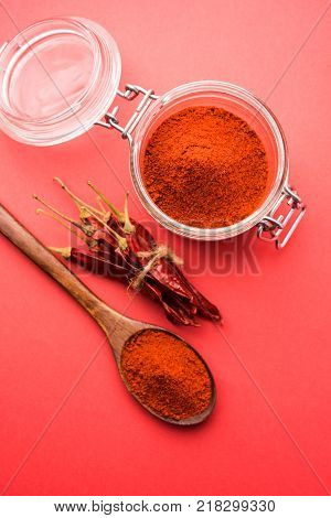 Red Chilly Powder in a bowl with dried red chillies over colourful background or pile of red chilli powder over plain background