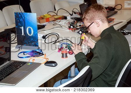 MOSCOW/ RUSSIA - DECEMBER 13, 2017. Schoolboy making a robot with the electric soldering iron during the  robotics competitions.