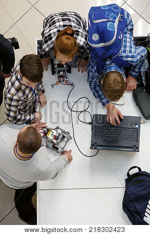MOSCOW/ RUSSIA - DECEMBER 13, 2017. Group of children with laptop, programming the robot at robotics competitions.