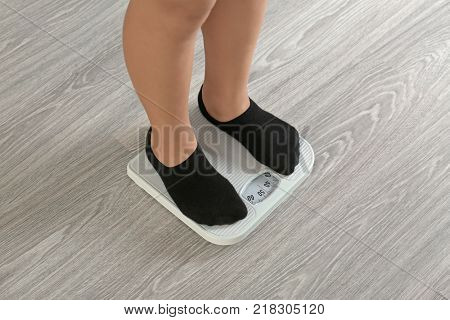 Legs of overweight boy standing on scales at home