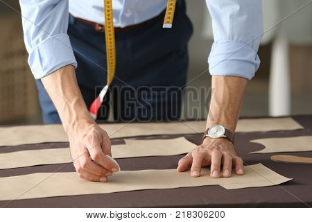 Young tailor working with sewing pattern in atelier