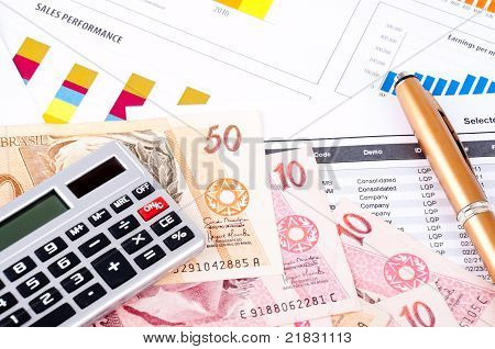 Foglio grafico e dati finanziario. Denaro brasiliano e penna.