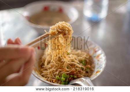 Fried Hokkien Noodles tong by chopsticks ready to eat in the southern of Thailand Phuket local Food