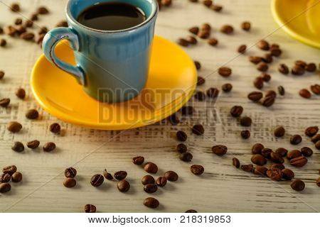 coffee cups with diferent colors with coffee beans liyng in the background