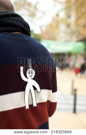 young man in the street with a paper man in his back as a prank for the dia de los inocentes, the innocents day, a feast held in spain, hispanic america and philippines equivalent to april fools day