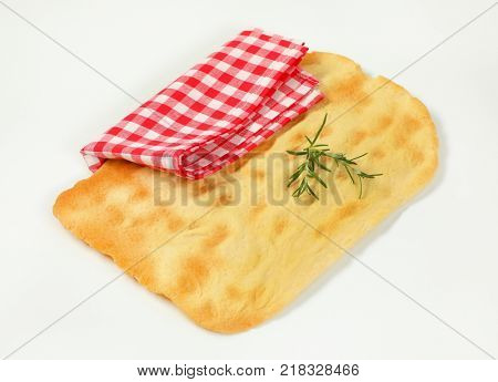 piece of traditional Tuscan flatbread (Ghiottina Toscana) and checkered place mat on white background