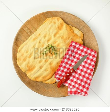two pieces of traditional Tuscan flatbread (Ghiottina Toscana) and kitchen knife on round wooden cutting board