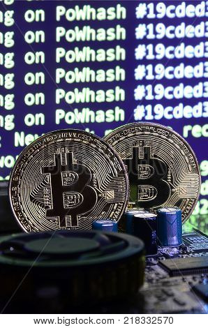 The digital process of cryptocurrency mining by using the GPUs. Bitcoins and video card on a working display and mining screen