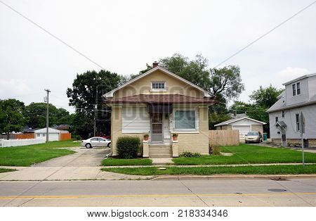 JOLIET, ILLINOIS / UNITED STATES - JULY 26, 2017: A small, brick, Cape Code style single family home, with a driveway, on Plainfield Road in Joliet.