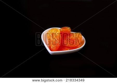 Delicious dried organic apricots on bowl isolated on black background