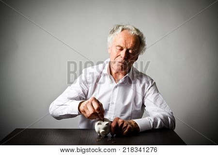 Senior man holding piggy bank. Financial security planning concept.