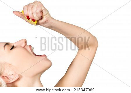 Young Woman Squeezing Lemon Juice into her Mouth Isolated on White Background. Copy Space
