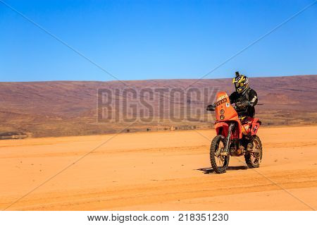 Ait Saoun Morocco - February 22 2016: Unidentified man in helmet riding bike in Ait Saoun desert of Morocco.