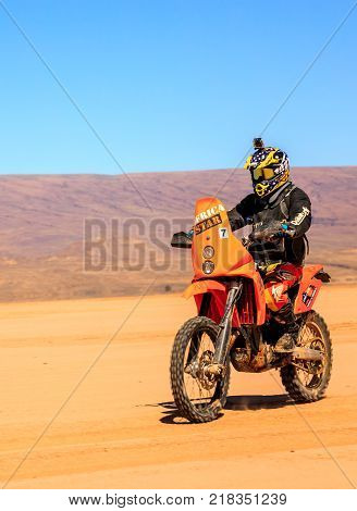 Ait Saoun Morocco - February 22 2016: Unidentified man in helmet riding bike in Ait Saoun desert of Morocco.