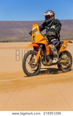 Ait Saoun Morocco - February 22 2016: Unidentified man in helmet riding bike in Ait Saoun desert of Morocco.