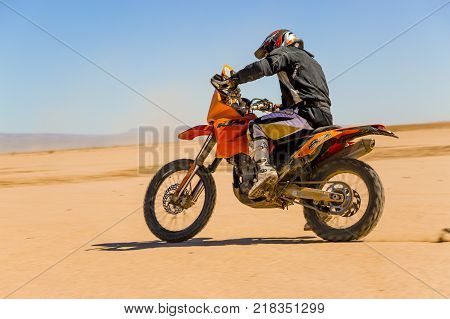 Ait Saoun Morocco - February 22 2016: side view of man in helmet riding bike in Ait Saoun desert of Morocco.