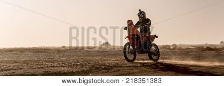 Ait Saoun Morocco - February 22 2016: Panoramic view of Man riding bike in the sand during late evening sunset at Ait Saoun desert Morocco.